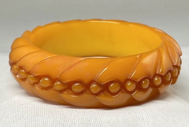 Translucent butterscotch bakelite bangle in a pinwheel pattern and additional carving of raised dots